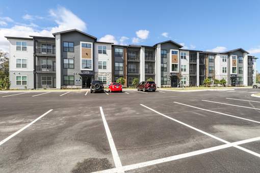 A parking lot in front of a multi-story apartment building.at The Liliana Apartment Homes, Pooler Georgia