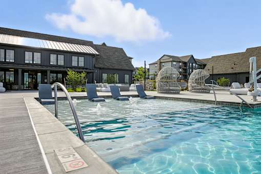 A pool with a wooden deck and a building in the background at The Garrison Luxury Apartment Homes, Fountain, CO 80817
