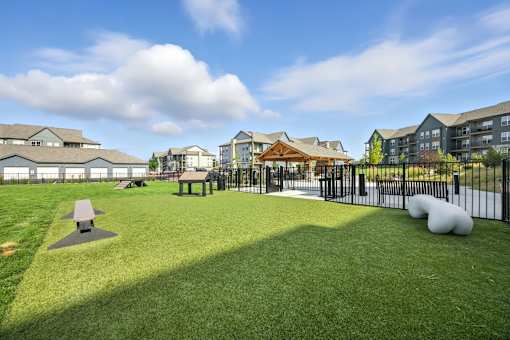 A park with a grassy area, picnic tables, and a playground at The Garrison Luxury Apartment Homes, Fountain, CO 80817