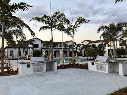 A white outdoor kitchen area with palm trees in the background.