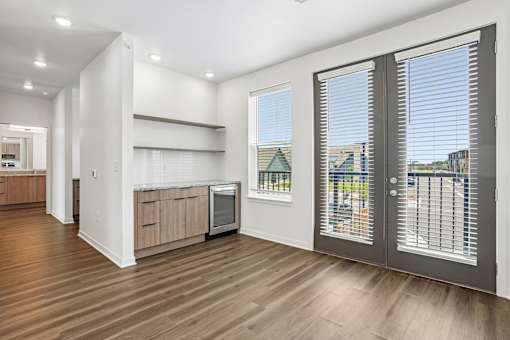 A kitchen with a wooden floor and a window with blinds.