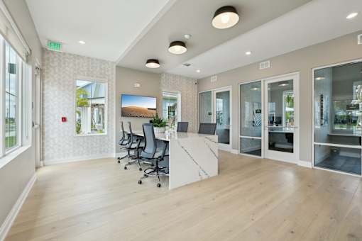 A room with a desk, chairs, and a television.