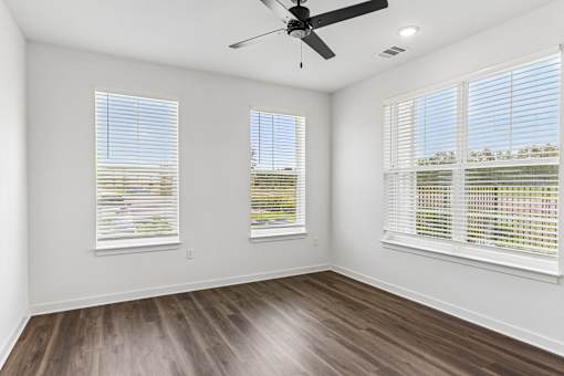Bright empty bedroom with ceiling fan and windows at Velara Luxury Apartments, Florida