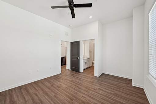 A room with a ceiling fan and wooden flooring.