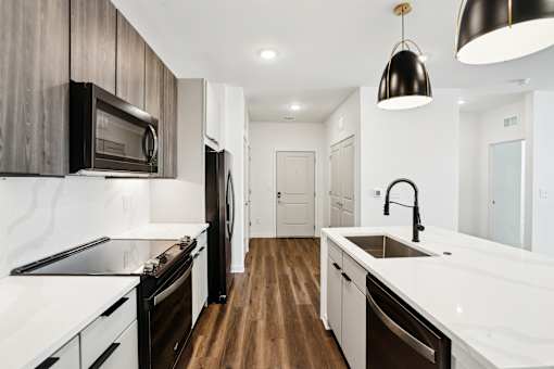 A modern kitchen with dark wood cabinets and white countertops. at The Pullman Luxury Apartments, Atlanta, 30349