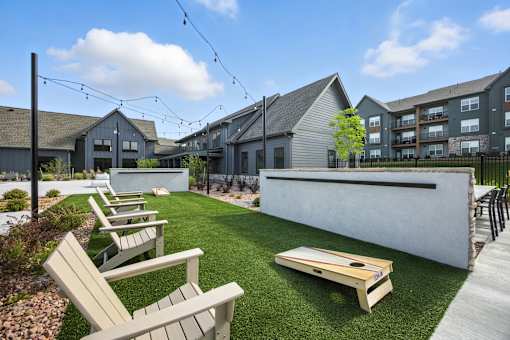 A sunny day at a park with wooden benches and a shuffleboard table at The Garrison Luxury Apartment Homes, Fountain, CO 80817