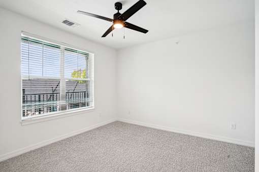 A room with a ceiling fan and a window with blinds. at The Pullman Luxury Apartments, Atlanta