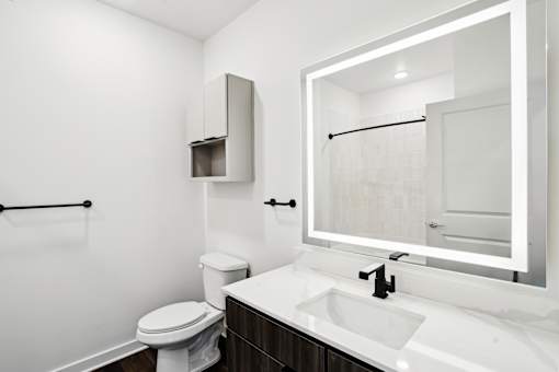 A white toilet sits next to a sink in a bathroom. at The Pullman Luxury Apartments, Atlanta, 30349