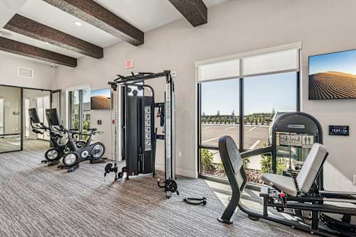 A gym with a treadmill, exercise bike, and other equipment at The Stadler Luxury Apartments, Florida