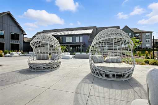 Two white outdoor chairs are in front of a building at The Garrison Luxury Apartment Homes, Fountain, CO 80817