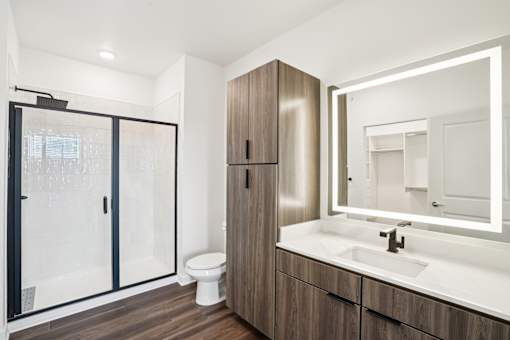 A modern bathroom with a walk-in shower, wooden cabinet, and a white sink. at The Pullman Luxury Apartments, Atlanta, Georgia
