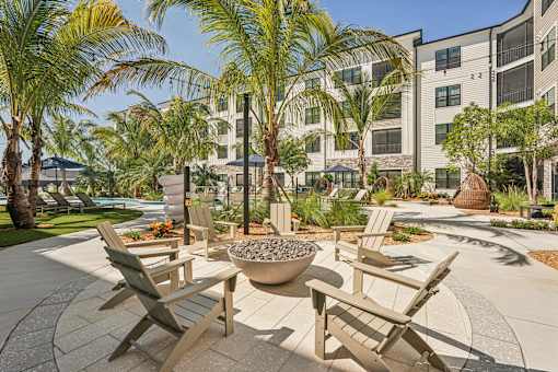 A patio with chairs and a fire pit in front of a building at The Stadler Luxury Apartments, Bradenton, Florida