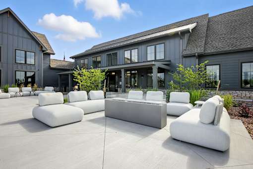 A modern outdoor seating area with white cushioned furniture in front of a grey building at The Garrison Luxury Apartment Homes, Fountain, CO 80817