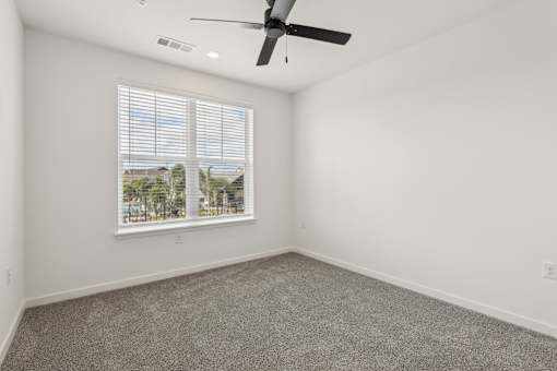 A room with a ceiling fan and a window with blinds.