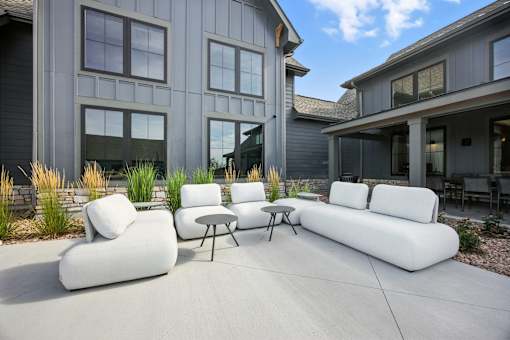 A white couch and table are on a patio in front of a house at The Garrison Luxury Apartment Homes, Fountain, CO 80817