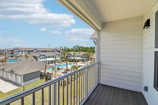 Covered balcony with view of pool and palm trees at Velara Luxury Apartments, Florida