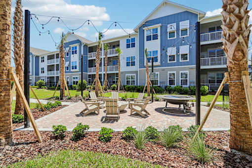 Outdoor fire pit area with adirondack chairs and string lights at Velara Luxury Apartments, Ponte Vedra Beach, FL 32081