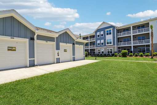 Detached garages and apartment buildings with lawn at Velara Luxury Apartments, Ponte Vedra Beach, FL
