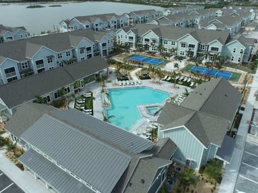 A large swimming pool is surrounded by a covered patio and a building.
