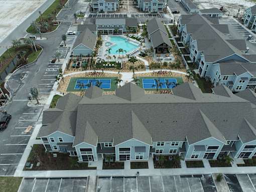 An aerial view of a residential complex with a pool and a parking lot.
