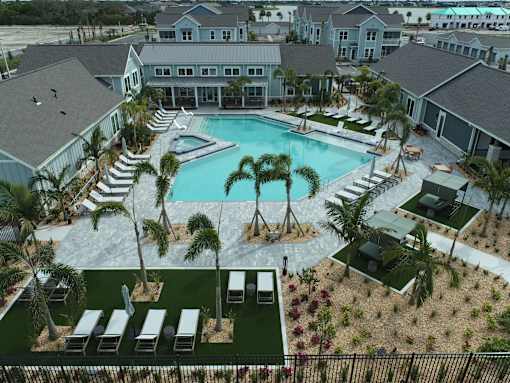 A pool surrounded by palm trees and lounge chairs.