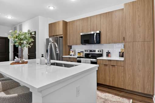 A modern kitchen with wooden cabinets and a white countertop.at The Logan Luxury Apartments, Nampa, ID, 83651