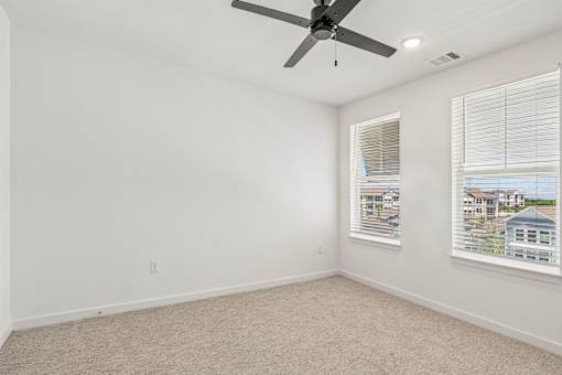 Empty bedroom with two windows and ceiling fan at Velara Luxury Apartments, Florida