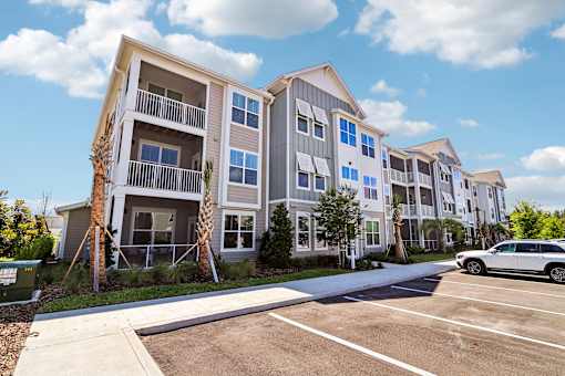 Modern apartment building exterior with parking and landscaping at Velara Luxury Apartments, Ponte Vedra Beach, FL