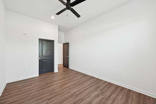 A room with a ceiling fan and wooden flooring.