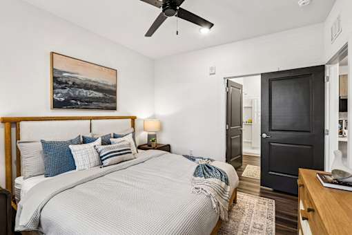 Bedroom with wood bed frame and open bathroom door at Velara Luxury Apartments, Ponte Vedra Beach, 32081