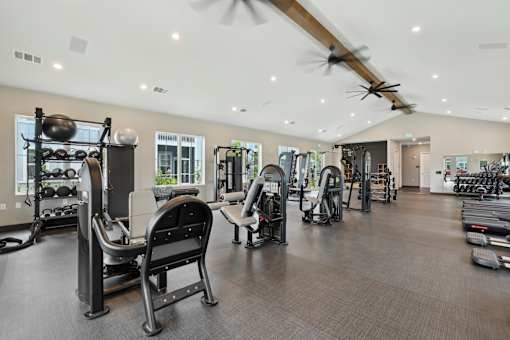 A gym with a variety of equipment including treadmills, weights, and exercise machines.