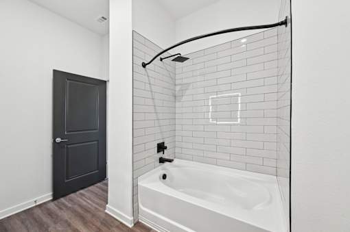 A white bathroom with a black door and a white tub.