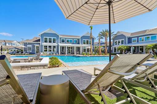 Pool deck with lounge chairs umbrellas and fire feature at Velara Luxury Apartments, Florida, 32081