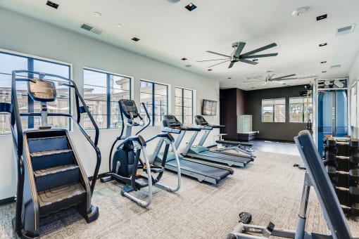 a gym with cardio equipment and windows in a building  at Grandstone at Sunrise, Peoria