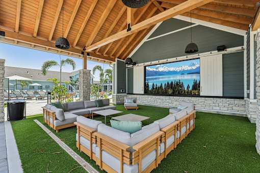A wooden patio with a couch and a television screen.