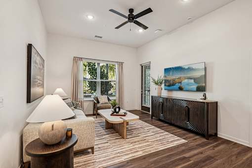 A living room with a ceiling fan and a painting of a lake at The Stadler Luxury Apartments, Florida 34210