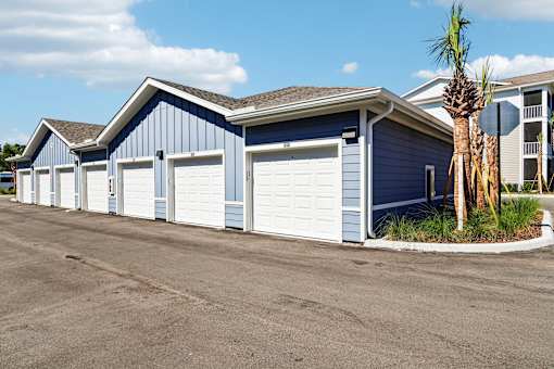 Detached garages with white doors and blue siding at Velara Luxury Apartments, Ponte Vedra Beach, FL