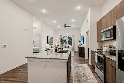 A modern kitchen with a marble countertop and stainless steel appliances at The Stadler Luxury Apartments, Bradenton, FL