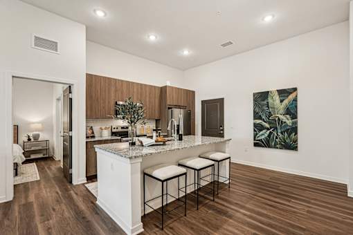 A kitchen with a white island and bar stools at The Stadler Luxury Apartments, Bradenton
