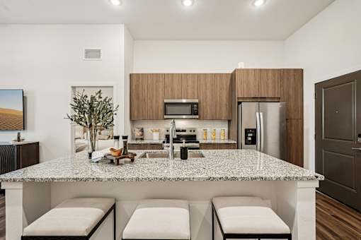 A modern kitchen with a granite countertop and stainless steel appliances at The Stadler Luxury Apartments, Bradenton, Florida