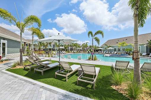 A poolside area with lounge chairs and palm trees.
