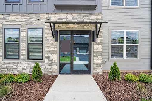 A modern house with a stone wall and a glass door. at The Pullman Luxury Apartments, Georgia