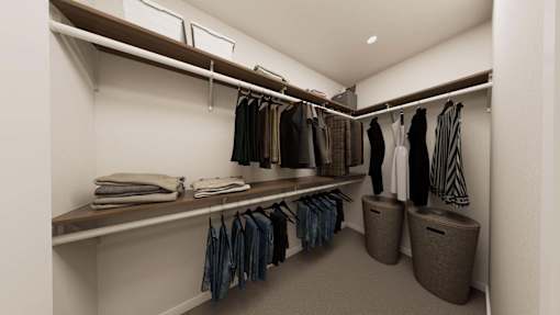 A walk in closet with clothes hanging and folded on shelves.