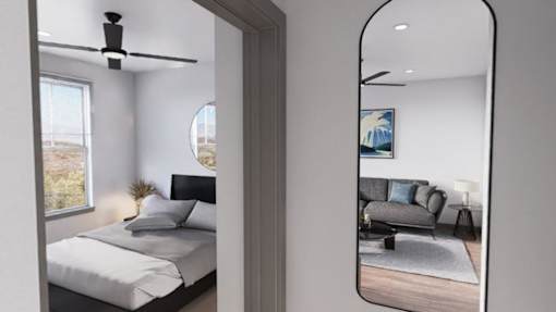 A bedroom with a bed, a ceiling fan, and a mirrored wall at Refinery at Pointe17 Apartments, Arizona