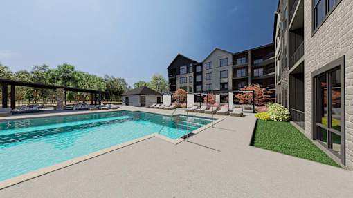 A swimming pool surrounded by a grassy area and buildings.