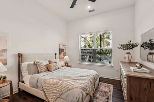 A bedroom with a bed, nightstand, and a window with blinds at The Stadler Luxury Apartments, Bradenton, 34210