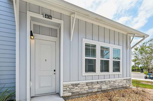 A house with a white door and windows is numbered 104. at The Sophia, Venice, FL