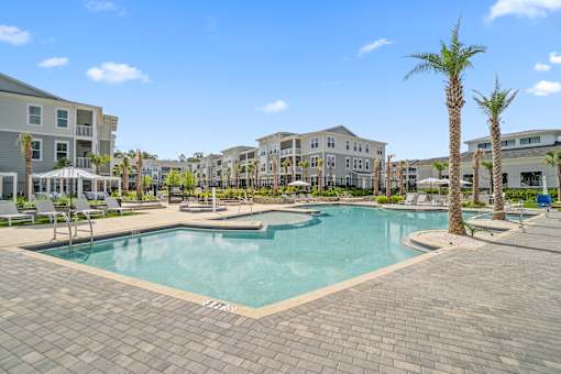 A large swimming pool surrounded by palm trees and lounge chairs.