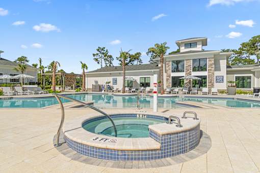 A hot tub sits in the middle of a pool surrounded by a tiled patio.