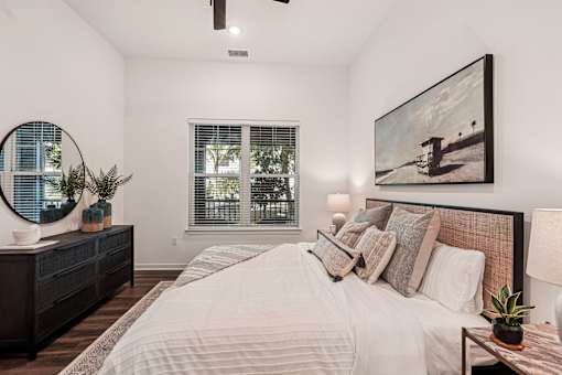 A bedroom with a large bed, a mirror, and a painting on the wall at The Stadler Luxury Apartments, Bradenton, FL